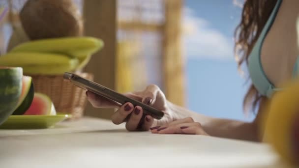 Молода жінка спілкується зі своїм смартфоном на пляжі — стокове відео