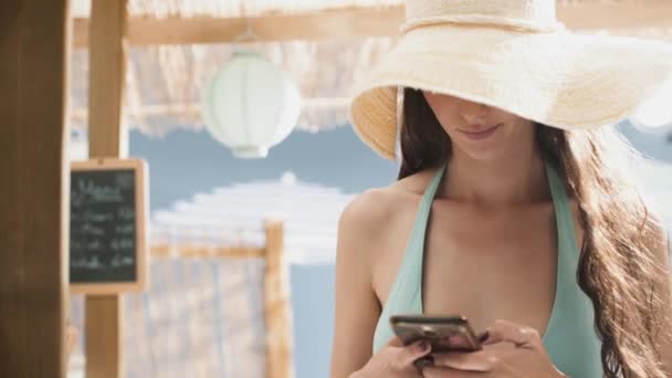 Jonge vrouw chatten met haar Smartphone op het strand — Stockvideo