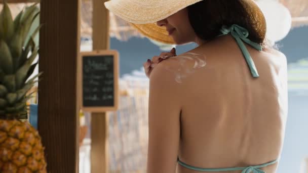 Young woman at the beach applying sunscreen cream — Stock Video