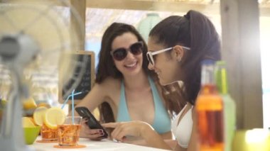 Bir akıllı telefon ile bağlanan plaj barda mutlu kızlar