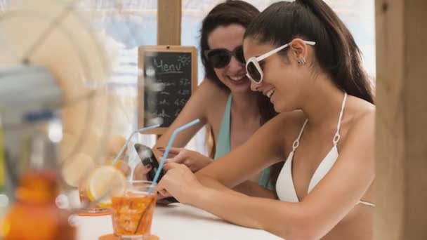 Chicas felices bebiendo juntas y tomando selfies en la playa — Vídeos de Stock