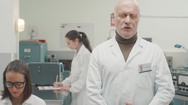 Bilim adamı laboratuvarda ayakta ve bir konuşma yapıyor — Stok video