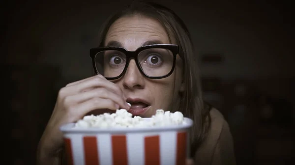 Женщина смотрит фильм ужасов и ест попкорн — стоковое фото