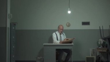 Sinirli iş adamı ofisinde gazete okuyor.
