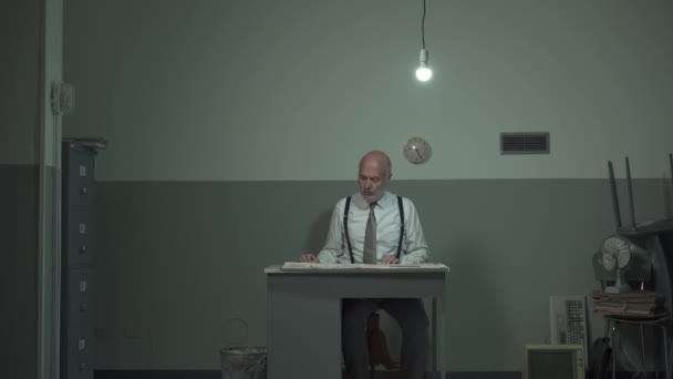 Разочарованный бизнесмен читает газету в своем офисе — стоковое видео