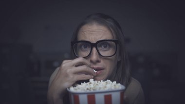 Korku filmi izleyen ve patlamış mısır yiyen bir kadın.