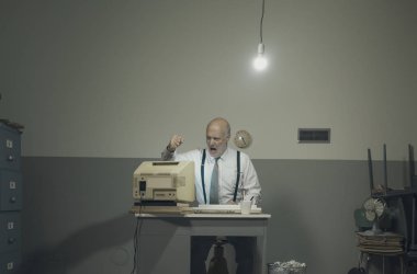 Öfkeli ofis çalışanı modası geçmiş bilgisayarına vuruyor.