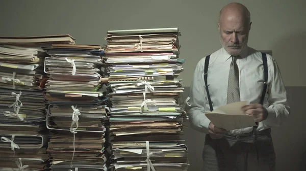 Empresario revisando archivos y montones de papeleo — Foto de Stock