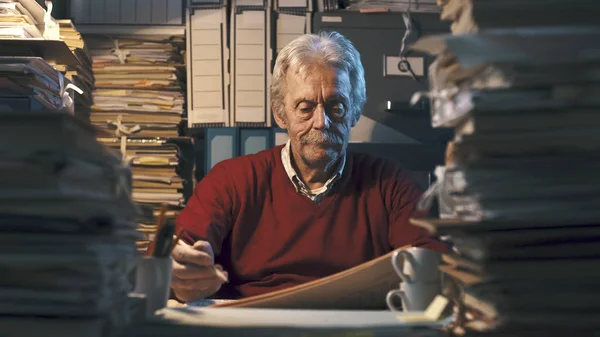 Senior office clerk surrounded by piles of paperwork — Stock Image Senior office clerk surrounded by piles of paperwork Stock Photo