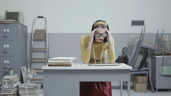 Businesswoman with headache in a messy office — Stock Photo, Image