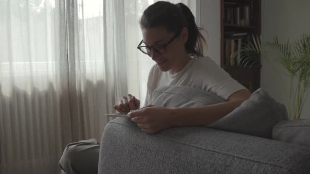 Mujer relajante en la sala de estar y conectar con su tableta — Vídeos de Stock