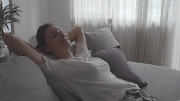 Szczęśliwa zrelaksowana kobieta leżąca na kanapie w domu — Wideo stockowe