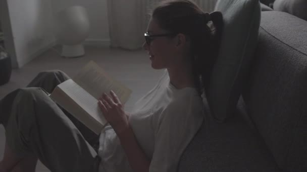 Vrouw die op de vloer zit en een boek leest — Stockvideo