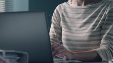 Ofis masasında oturan ve maske takan bir kadın.