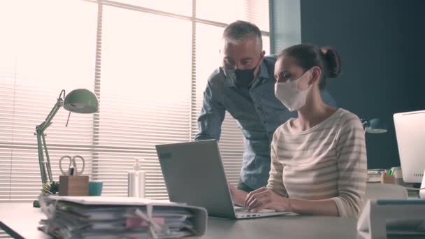 Biznesmeni pracujący w biurze i noszący maski na twarz — Wideo stockowe