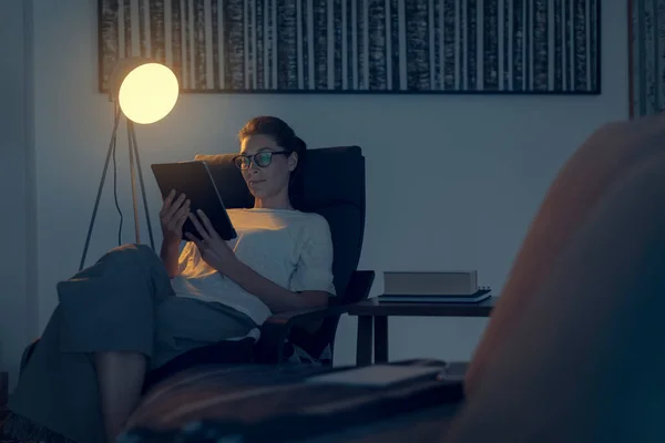自宅でリラックスしている女性は アームチェアに座ってデジタルタブレット 現代的なデザインのインテリアと接続しています — ストック写真
