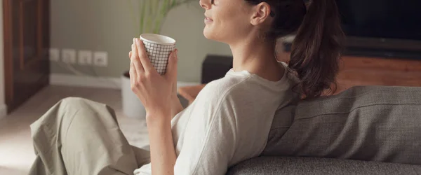 Ung Kvinna Koppla Hemma Soffan Och Dricka Kopp Kaffe Hon — Stockfoto