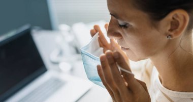 Ofiste çalışan ve koruyucu bir cerrahi maske takan bir kadın. Coronavirus covid-19 önleme.