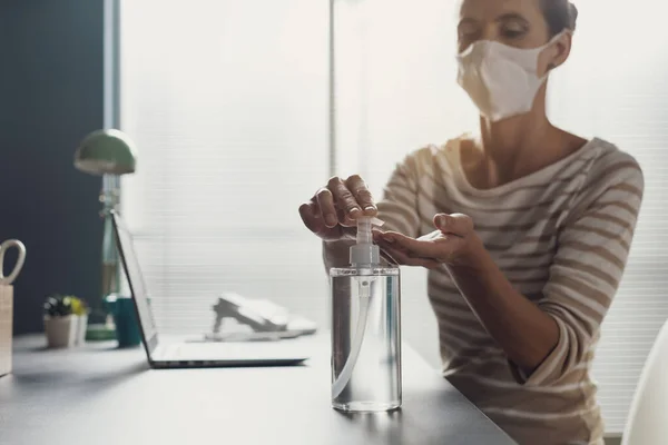 女性はオフィスの机に座って 彼女の手に消毒剤を適用 コロナウイルスCovid 19予防 — ストック写真