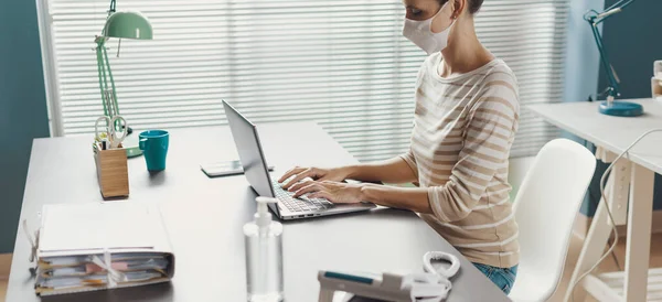 在办公室工作的女商人戴着防护面罩 坐在办公桌前 在笔记本电脑上打字 — 图库照片