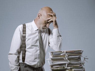 Endişeli iş adamı bir yığın evrak, bürokrasi ve idari konsepte dayanıyor.