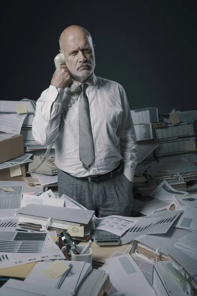 Запутавшийся Офисный Работник Отвечает Телефонные Звонки Окружен Множеством Бумажной Работы — стоковое фото