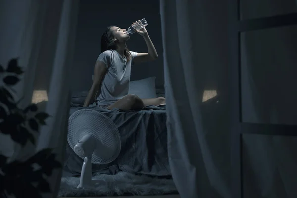 不眠症と熱に苦しんでいる若い女性 彼女はベッドに座って 新鮮な水を飲んでいます — ストック写真
