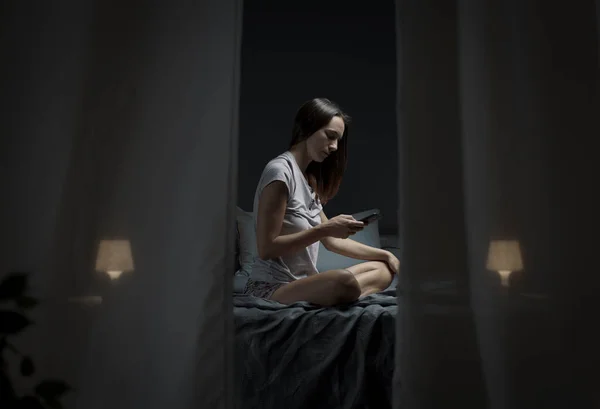 Молода Жінка Сидить Ліжку Вночі Спілкується Своїм Смартфоном — стокове фото