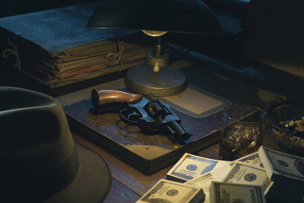 1950s film noir style desktop with revolver and cash money: crime, gangsters and thriller concept