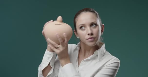Young businesswoman holding a clay money box — Stock Video