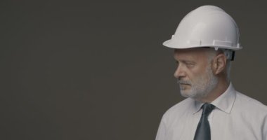 Gülümseyen mühendis kameraya bir şey sunuyor.