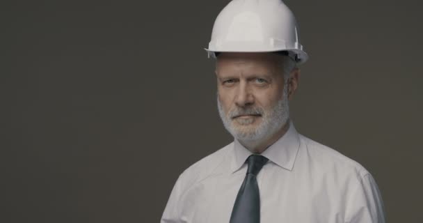 Уверенный бизнесмен и инженер позирует с защитным шлемом — стоковое видео