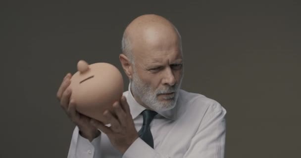 Бизнесмен проверяет свои сбережения в глиняной ячейке — стоковое видео