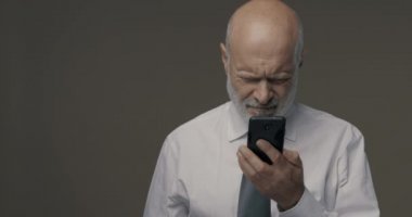 Orta yaşlı bir adam akıllı telefonunu kullanmakta zorlanıyor ve görme sorunları yaşıyor.
