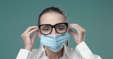 Cerrahi maske takan ve gözlük takan bir kadın.