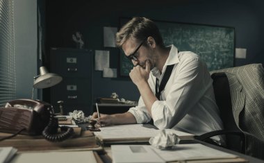 Zeki genç matematikçi ofis masasında oturup ödevlerini gözden geçiriyor ve yeni formüller üzerinde çalışıyor.
