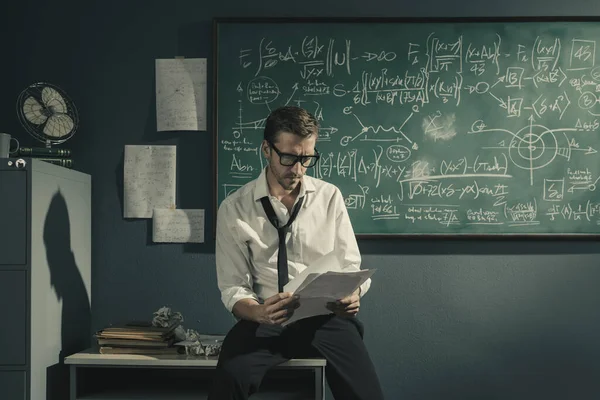 Young researcher studying mathematics in his office, he is checking papers, solving problems and discovering new theories