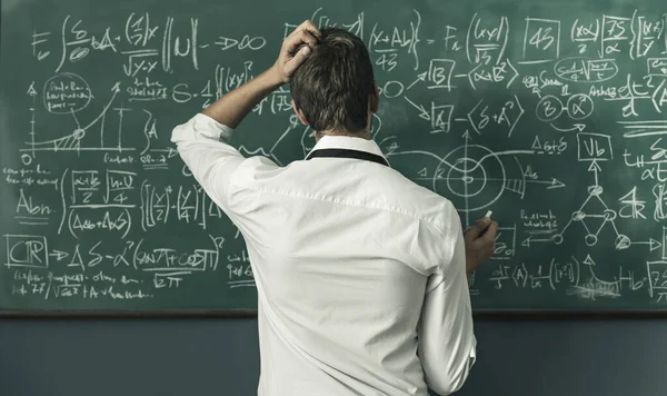 年轻的数学家在黑板上解决问题和写公式 — 图库照片