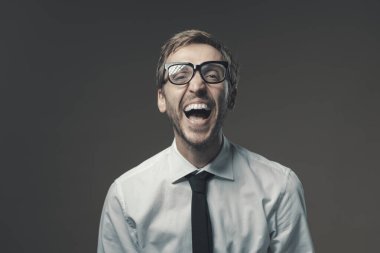 Genç işadamı yüksek sesle gülüyor ve kameraya bakıyor.