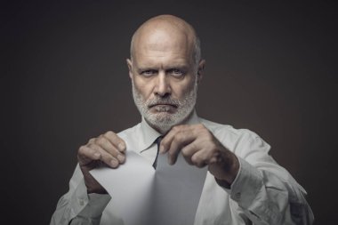 Kızgın şirket işadamı sözleşmeyi yırtıp kameraya bakıyor.