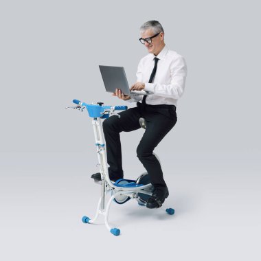 Verimli gülümseyen bir işletme yöneticisi bisiklet üzerinde çalışıyor ve bir dizüstü bilgisayarla çalışıyor.