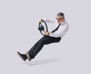 Hayali bir araba kullanan komik bir işadamı, direksiyonu tutuyor ve havada süzülüyor.