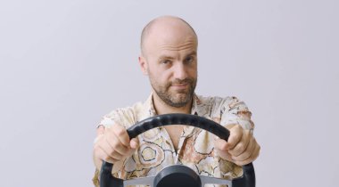 Elinde direksiyon tutan ve görünmez bir araba kullanan gülümseyen bir adam kameraya bakıyor, izole edilmiş.