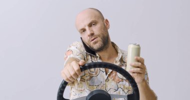 Dikkatsiz sürücü araba kullanırken içki içiyor ve telefonunu kullanıyor, beyaz arka planda izole edilmiş.