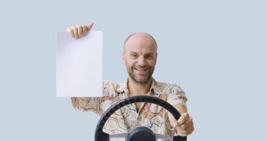 Gülümseyen adam araba kullanıyor ve sigorta belgelerini gösteriyor.