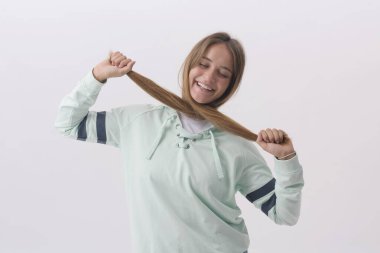 Sağlıklı, uzun saçlarıyla oynayan, beyaz arka planda soyutlanmış genç bir kadının portresi.