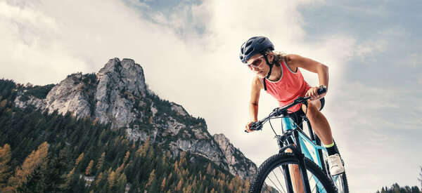 Young Female Athlete In Professional Sportswear, Riding Her Mountain Bike With Determination On Scenic Mountain Trails