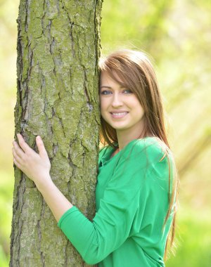 Güzel genç kadın kucaklama ağaç