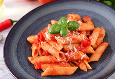 Lezzetli arabiata makarna peynir ve fesleğen yaprakları ile