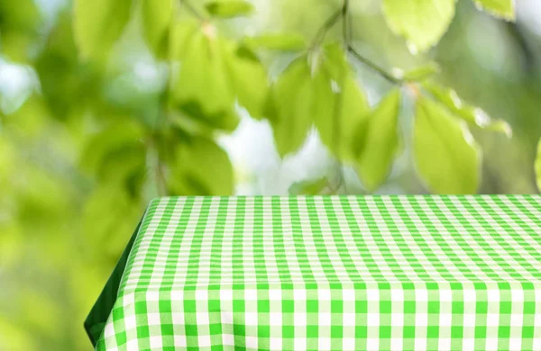 Leerer Tisch Mit Farbig Karierter Tischdecke Und Unscharfem Natürlichen Hintergrund — Stockfoto